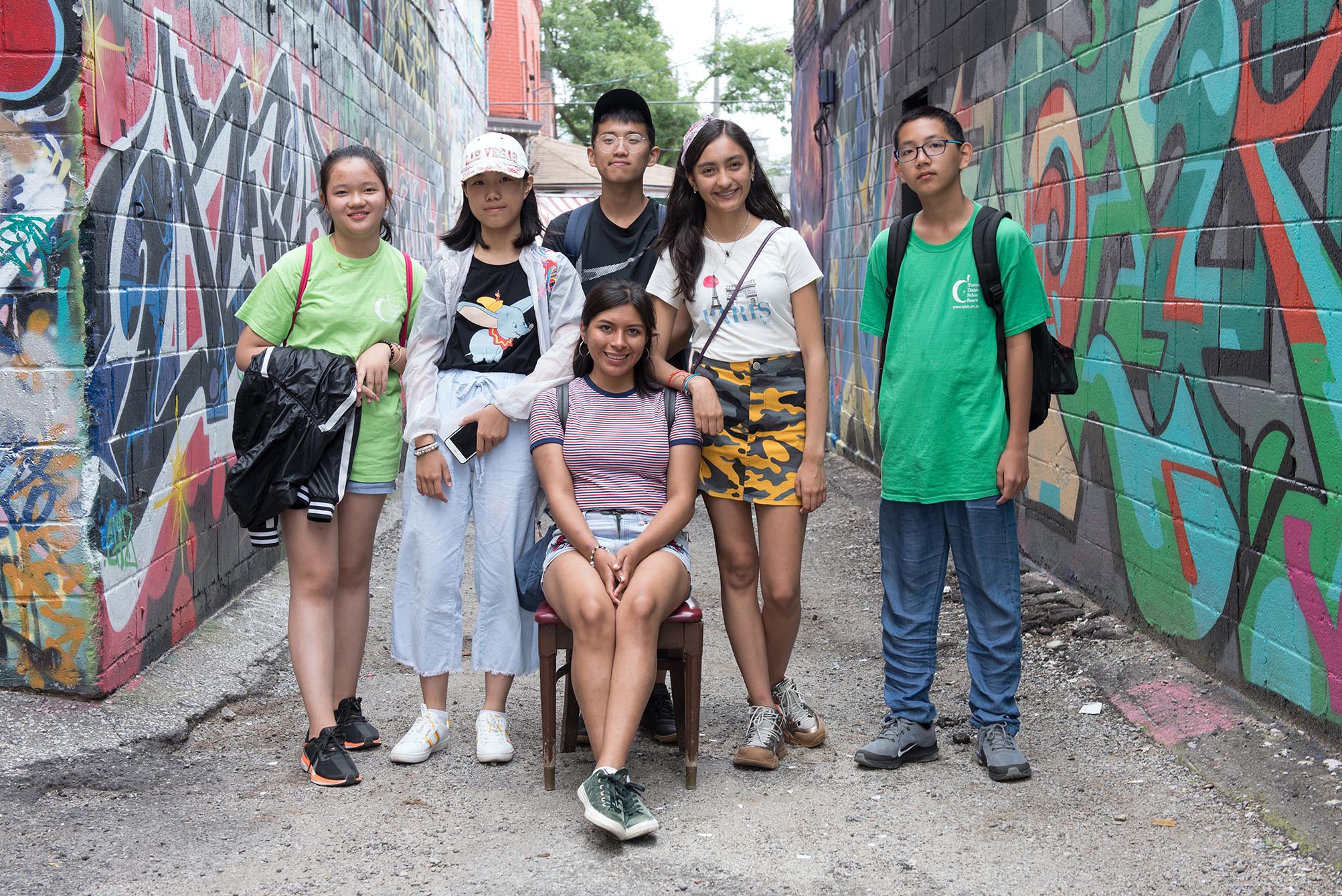 Group of students standing in alley way with graffiti on both sides  Open Gallery